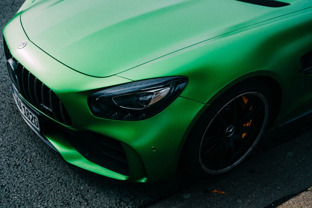 Close-up of a green luxury Mercedes sports car with a focus on the headlight.