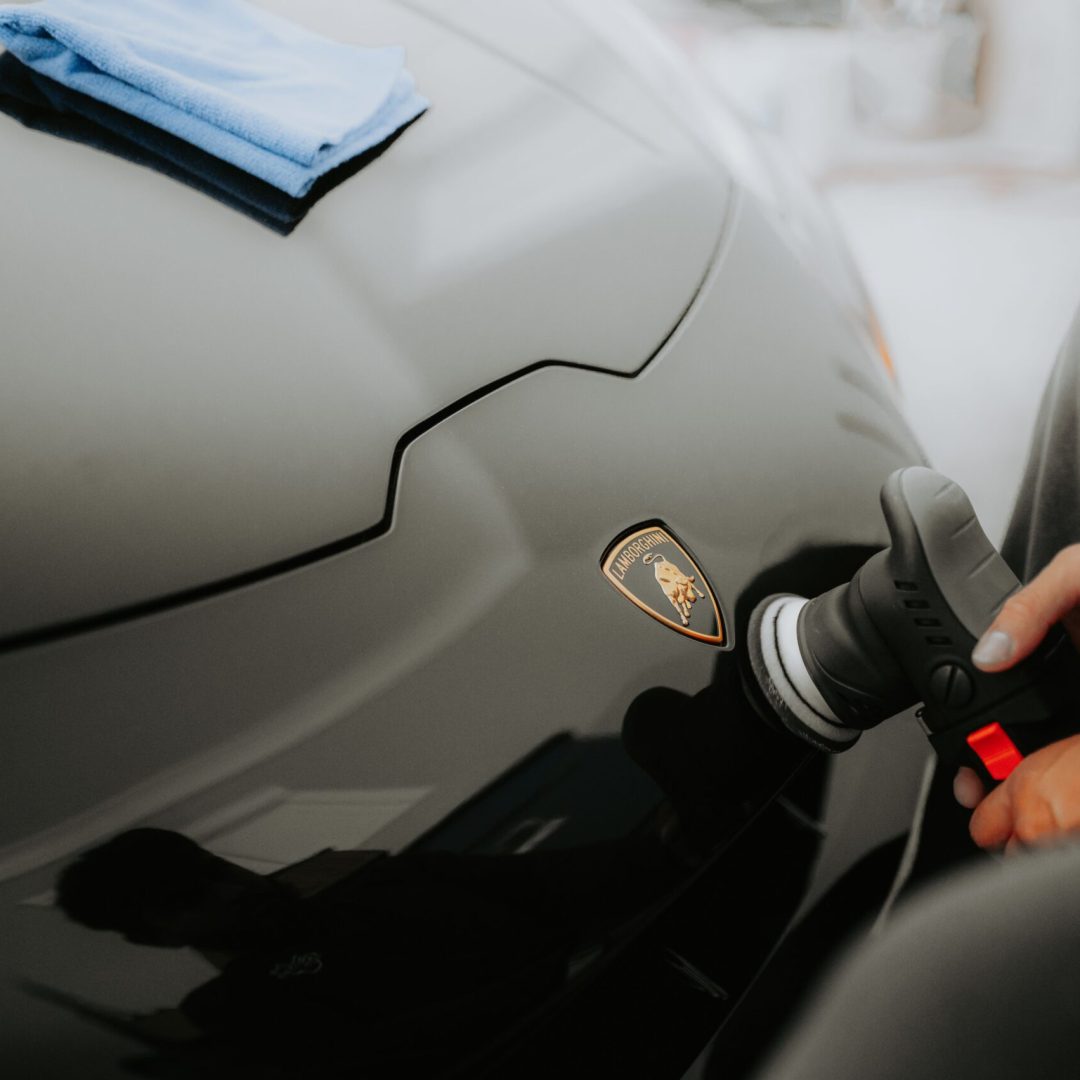 Detailed shot of a Lamborghini being polished, showcasing an automotive care process in a garage.