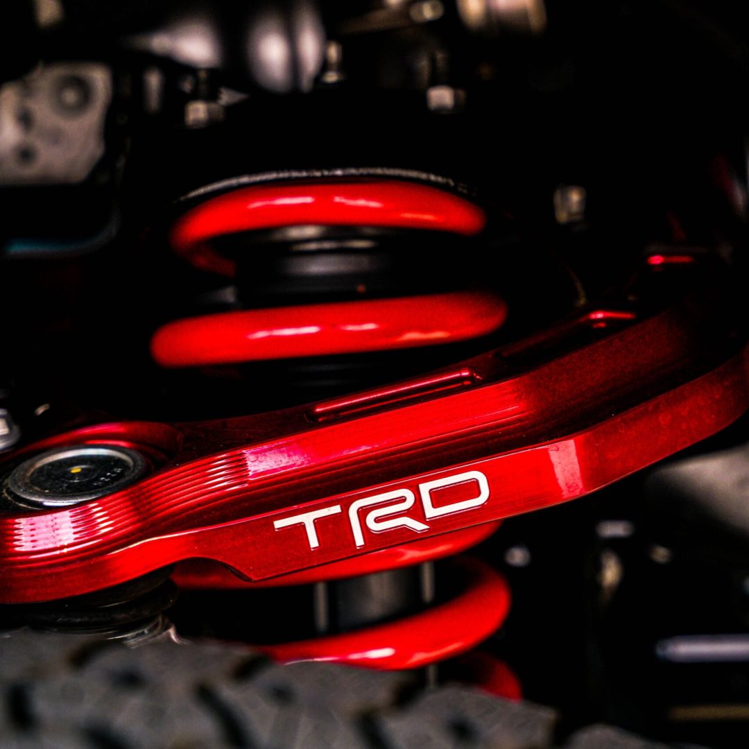 Close-up of a vibrant red TRD suspension system highlighting car engineering details.
