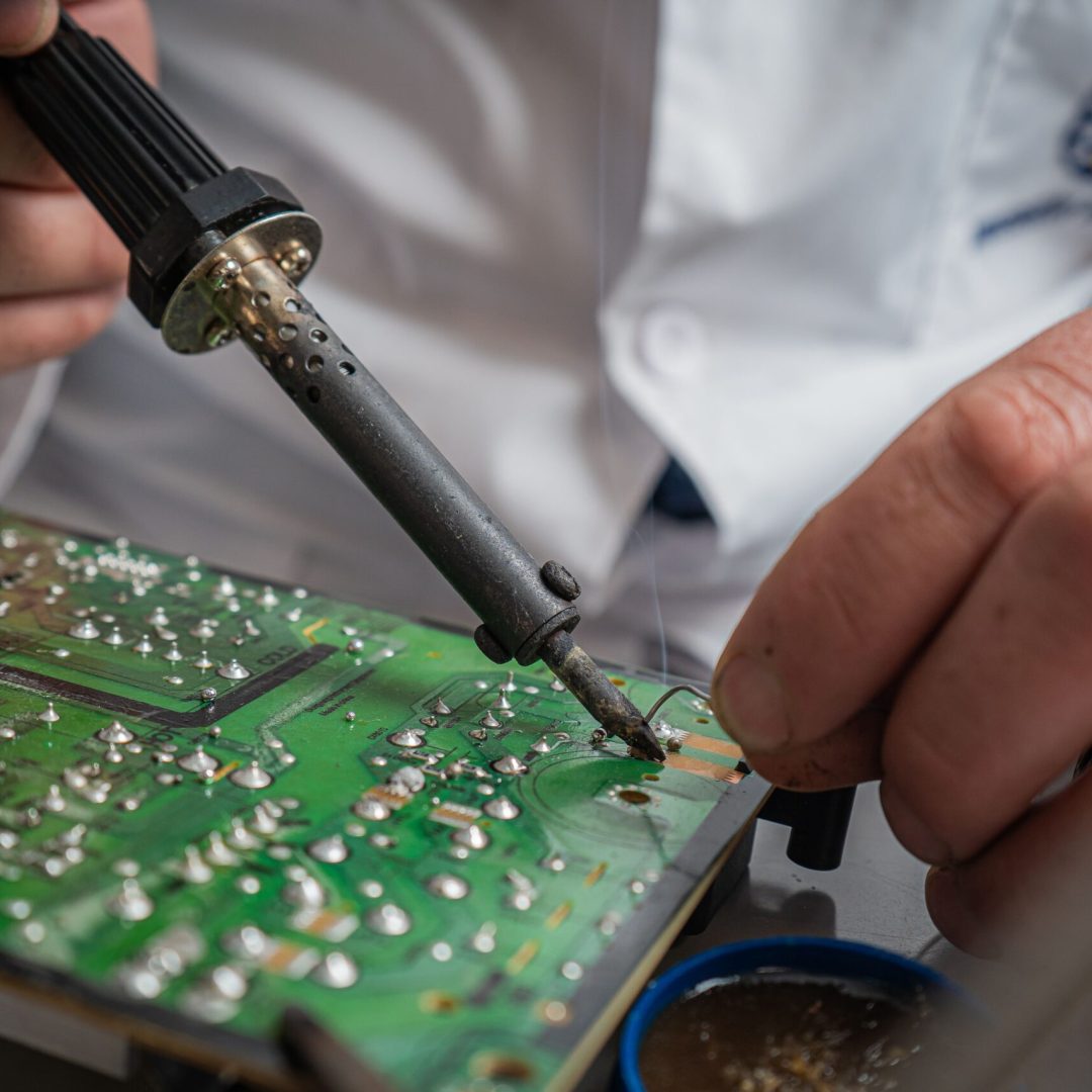 Technician performing precise soldering on a circuit board for electronics repair.