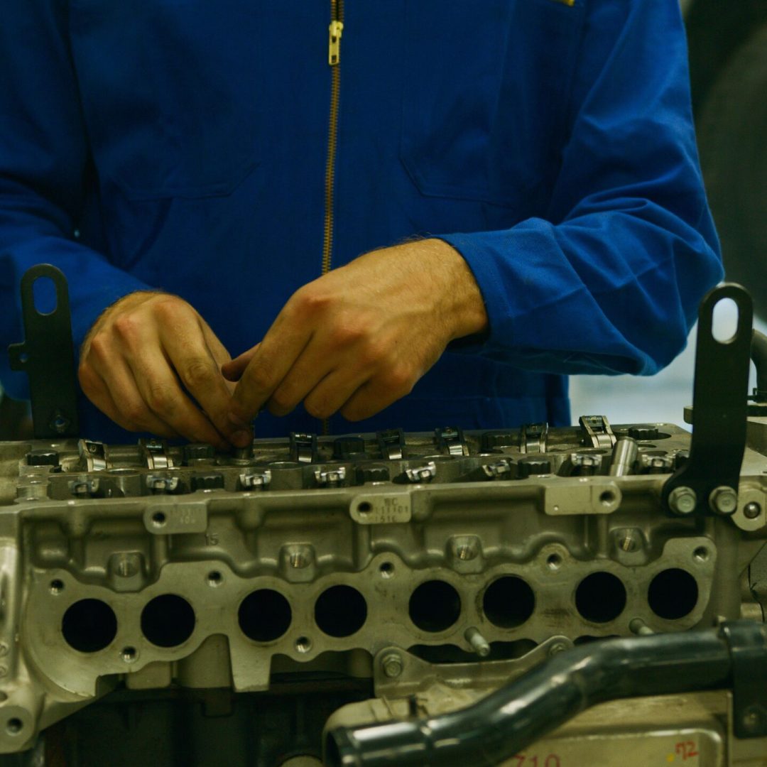 Close-up of a mechanic repairing an engine in a garage setting.